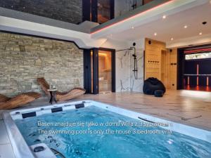 a hot tub in a room with a stone wall at LK Forest Villa luksusowe domy z basenem z jacuzzi, sauną, grotą solną, salą bilardową i ogrodem in Łapsze Niżne