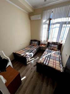 twee bedden in een kamer met houten vloeren en ramen bij Tatev in Jerevan