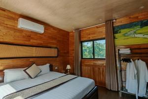宁平Hidden Valley Eco Retreat Trang An的一间带床的卧室，位于一间带木墙的房间里