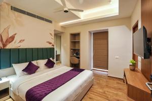 Un dormitorio con una cama grande y un televisor. en M Suites And Hotel, en Kochi