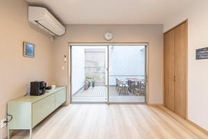 印西市にあるThe Penguinの時計のあるバルコニーへのドアがある空の部屋