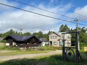 a house and a log cabin with a wheel in front at 北海道ゲストハウス川湯温泉6丁目 in Kawayu