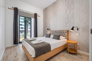 a bedroom with a large bed and a large window at Tanoeiros Residence by An Island Apart in Funchal