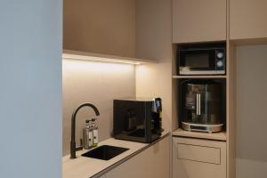 a kitchen with a microwave and a coffee maker at KINN Capsule - HER Space, Female Only in Singapore