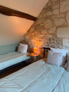 two beds in a room with a stone wall at Domaine de La Nouillière - Jacuzzi in Saint-Nicolas-de-Bourgueil
