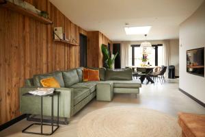a living room with a green couch and a table at Fokkemaat in Callantsoog