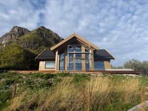 una casa en una colina con una montaña al fondo en Gimsøy Lodge,  19 fotos más