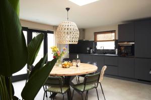 a kitchen with a table with chairs and aendant light at Fokkemaat in Callantsoog +8 photos