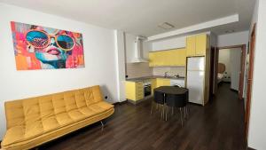 a living room with a yellow couch and a kitchen at la casa de pozo1 in Pozo Izquierdo