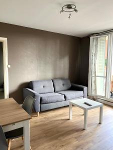 a living room with a couch and a table at Logement proche du Puy de Dôme avec parking privé in Clermont-Ferrand