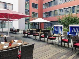 an outdoor restaurant with tables and chairs and umbrellas at Mercure Hotel Frankfurt Eschborn Helfmann-Park in Eschborn