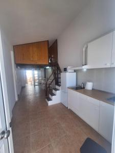 a kitchen with white cabinets and a dining room at Casa vista golf in Caleta De Fuste +4 photos
