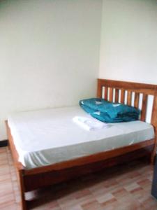a wooden bed with a blue blanket on it at Banana Grove Retreat in Moshi