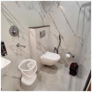 a white bathroom with a toilet and a sink at Hotel AV Ganges Varanasi - Walking Distance From BABA VISHWANATH TEMPLE #Wifi #Fully Air Conditioned & Spacious Rooms - Best Budget Hotel In Varanasi in Varanasi
