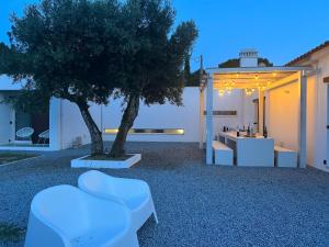 a garden with a tree and white furniture and a building at Fazenda do Pomar by Trip2Portugal in Montemor-o-Novo