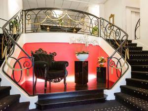 a staircase with a chair and a red wall at Mercure Lourdes Impérial in Lourdes