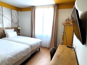 a bedroom with a bed and a desk and a window at Mercure Lourdes Impérial in Lourdes