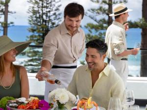 a man serving a woman a plate of food at Manly Pacific Sydney MGallery Collection in Sydney