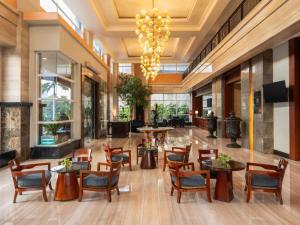 a lobby with tables and chairs and a chandelier at Novotel Semarang in Semarang