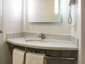 Un baño con lavabo, espejo y toallas. en ibis Araçatuba, en Araçatuba 72 fotos más