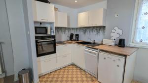 a kitchen with white cabinets and a stove top oven at Le Refuge - Petite maison de village in Kaysersberg