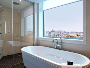 a bathroom with a bath tub and a window at Sofitel Luxembourg Le Grand Ducal in Luxembourg