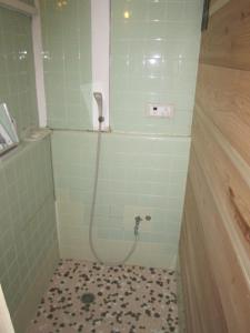 a small bathroom with a shower with a tiled floor at Taito Ryokan in Tokyo