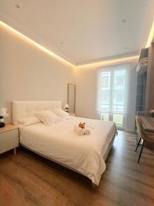 ビルバオにあるApartamento NUEVO Lujoso Suites Centro Bilbao Wifi ,Parking gratisのベッドルーム(花の飾られた白い大型ベッド付)
