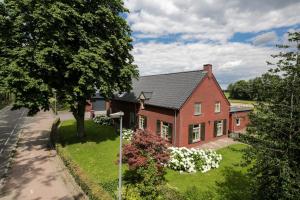 dom z czerwonej cegły z drzewem i ulicą w obiekcie Lokven Hoeve w mieście Vinkel