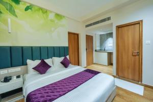 Un dormitorio con una cama grande con almohadas moradas. en M Suites And Hotel, en Kochi 20 fotos más
