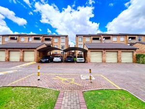 a parking lot in front of a building with cars at Centurion La Creme Apartments in Centurion