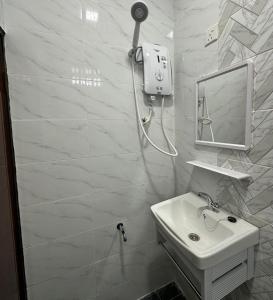 une salle de bain blanche avec un lavabo et une douche dans l'établissement cheta roomstay, à Gua Sai
