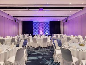 a banquet hall with white tables and chairs and a screen at Sofitel Fiji Resort & Spa in Denarau +236 photos