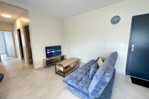 Una sala de estar con un sofá azul y un televisor. en Kavai City - brand new 2 bedr 2bth AC - Wi-Fi - parking, en Papeete