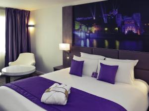 a hotel room with a large bed with purple pillows at Mercure Lyon Est Chaponnay in Chaponnay