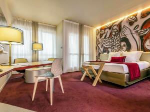a hotel room with a large bed and a desk at Mercure Limoges Centre in Limoges