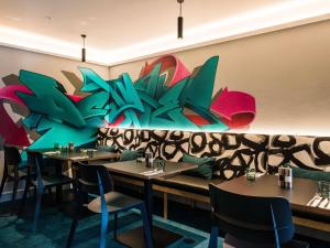 a restaurant with tables and chairs and a mural at Ibis Christchurch in Christchurch