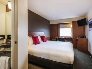 a hotel room with a large bed with red pillows at Ibis Christchurch in Christchurch