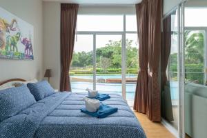 une chambre avec un lit bleu et une grande fenêtre dans l'établissement Boathouse Hua Hin Condo, à Ban Bo Fai (1) 153 autres photos