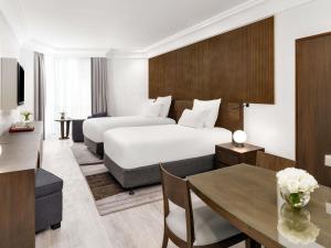a hotel room with a bed and a dining room at Zamzam Pullman Makkah in Mecca