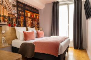 パリにあるMidnight Hôtel Parisのベッドルーム1室(大型ベッド1台、オレンジと白の枕付)