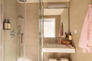 パリにあるMidnight Hôtel Parisの洗面台と鏡付きシャワーを備えたバスルーム