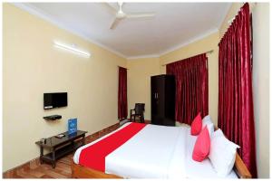 1 dormitorio con 1 cama grande y cortinas rojas en HOTEL PINK-Villa Near Budha Jayanti Park- with free wifi - Restaurant Facilities Available - Best Hotel In Bhubneshwar, en Cuttack