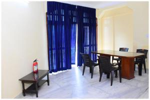 comedor con mesa, sillas y cortinas azules en HOTEL PINK-Villa Near Budha Jayanti Park- with free wifi - Restaurant Facilities Available - Best Hotel In Bhubneshwar, en Cuttack