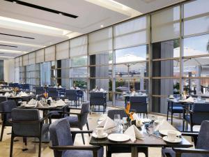 a restaurant with tables and chairs and large windows at Novotel Hyderabad Convention Centre in Hyderabad
