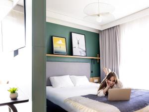 a little girl laying on a bed with a laptop at Aparthotel Adagio Annecy Centre in Annecy