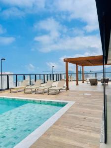 a swimming pool with chairs and a view of the ocean at Lindo Studio a 600m da praia in Guarujá +20 photos
