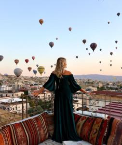 a woman standing on a balcony looking at hot air balloons at Virtus Cappadocia Hotel Göreme in Goreme