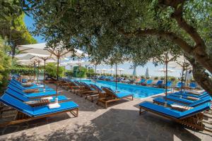 a row of blue lounge chairs next to a swimming pool at Hotel Majestic in Lido di Jesolo