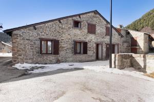 a stone house with a lot of snow in front of it at Maison de village Le Galbe in La Llagonne